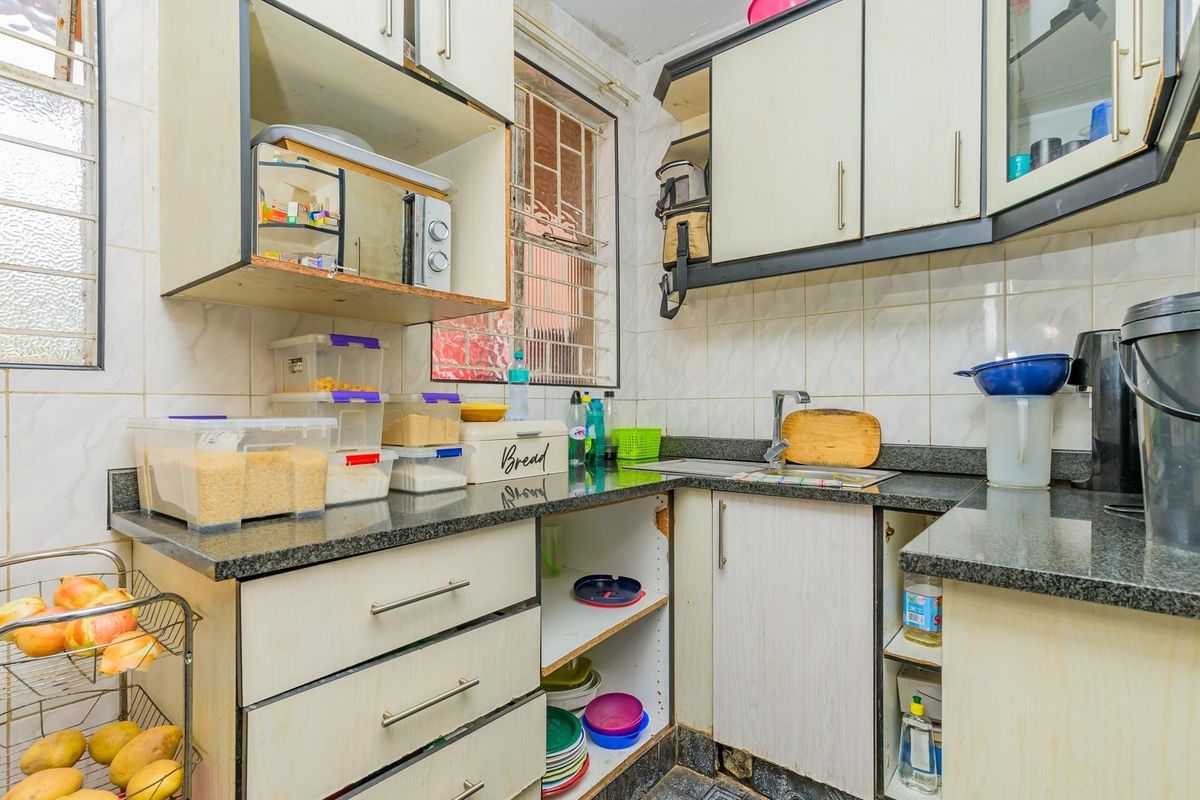 Compact kitchen featuring granite countertops, tiled backsplash, and built-in cabinetry. The space requires cosmetic updates to improve functionality and aesthetic appeal.