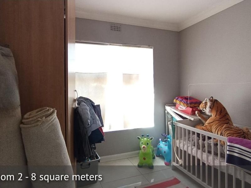 A compact bedroom featuring tiled flooring, a built-in cupboard, and neutral wall finishes, providing a functional space for a child or home office.
