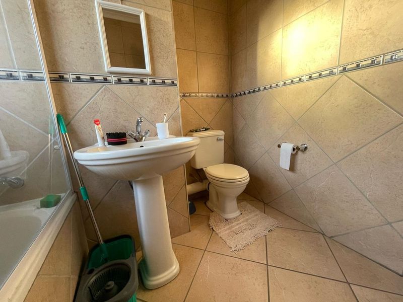 A functional bathroom featuring a pedestal basin, toilet, and tiled finishes throughout, providing a practical space for daily use.