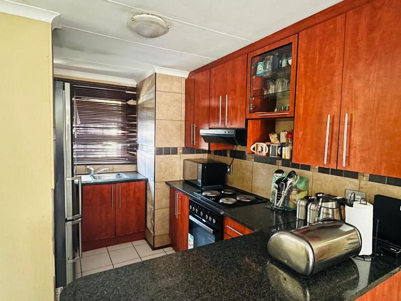 A functional kitchen featuring wood-finish cabinetry, granite countertops, a built-in oven with hob, and a tiled backsplash.