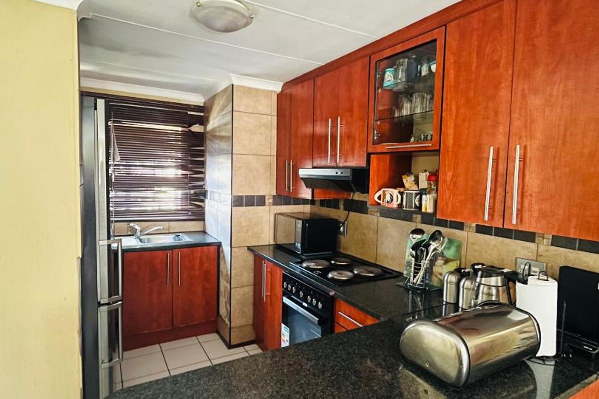 A functional kitchen featuring wood-finish cabinetry, granite countertops, a built-in oven with hob, and a tiled backsplash.