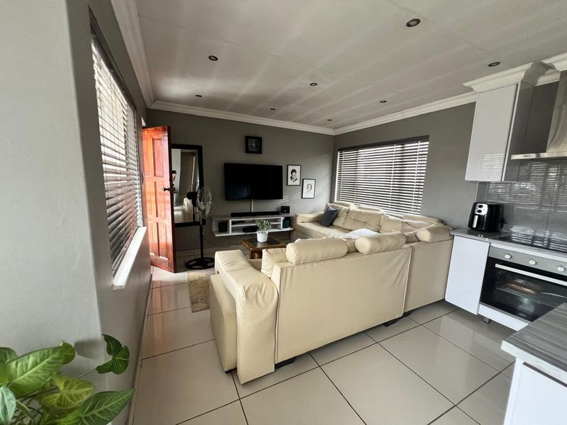 Open-plan living area featuring tiled floors, recessed lighting, and a compact kitchen with built-in oven and extractor fan.