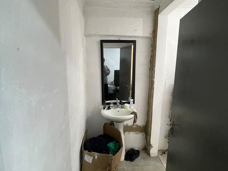 A small bathroom area featuring a pedestal basin and tiled flooring, currently requiring significant cosmetic repairs to the walls and ceiling.