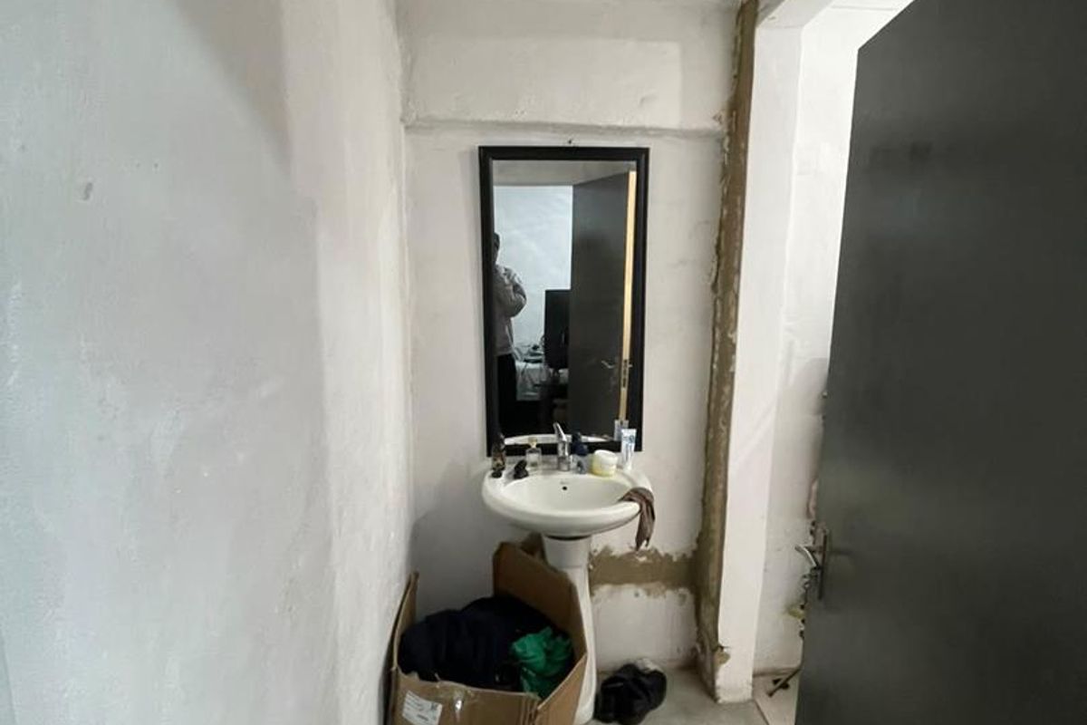 A small bathroom area featuring a pedestal basin and tiled flooring, currently requiring significant cosmetic repairs to the walls and ceiling.