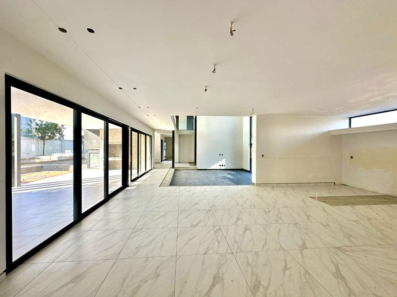 Spacious open-plan living area featuring large-format marble-look floor tiles and expansive floor-to-ceiling sliding glass doors leading to the outdoor patio.