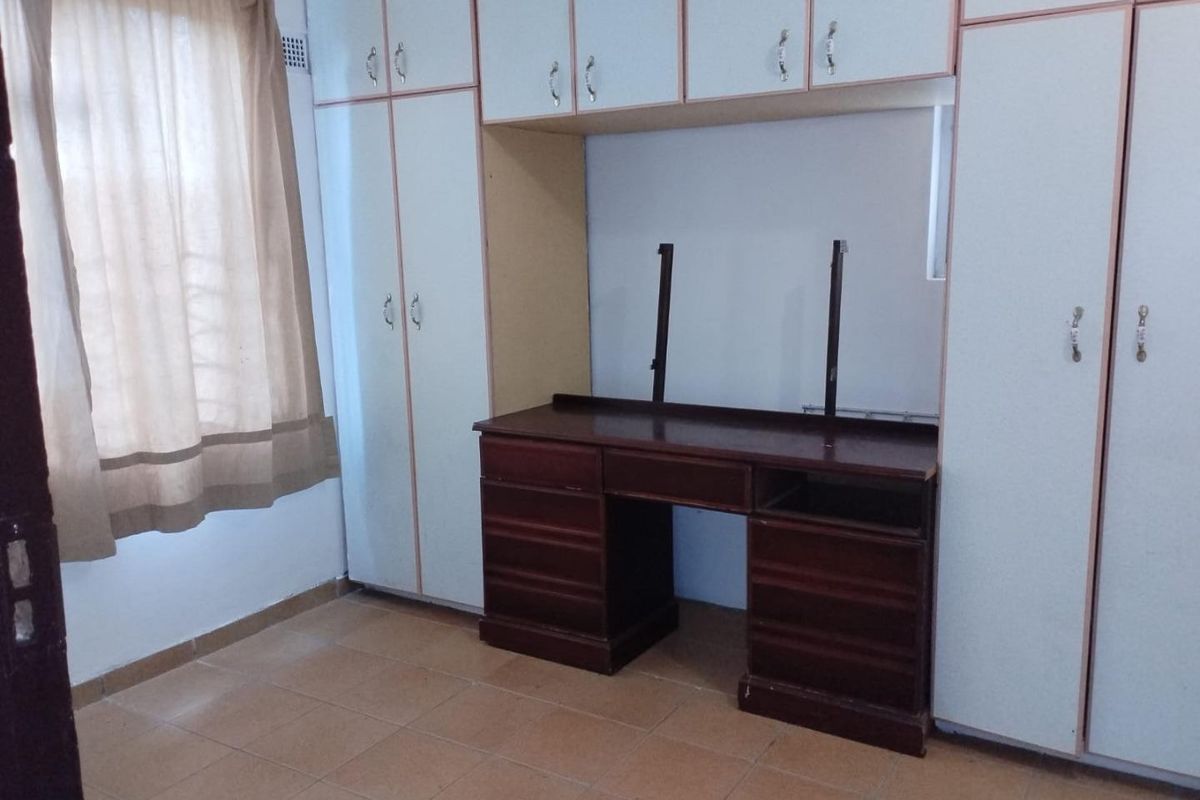 Bedroom featuring built-in cupboards with an integrated vanity unit and tiled flooring.
