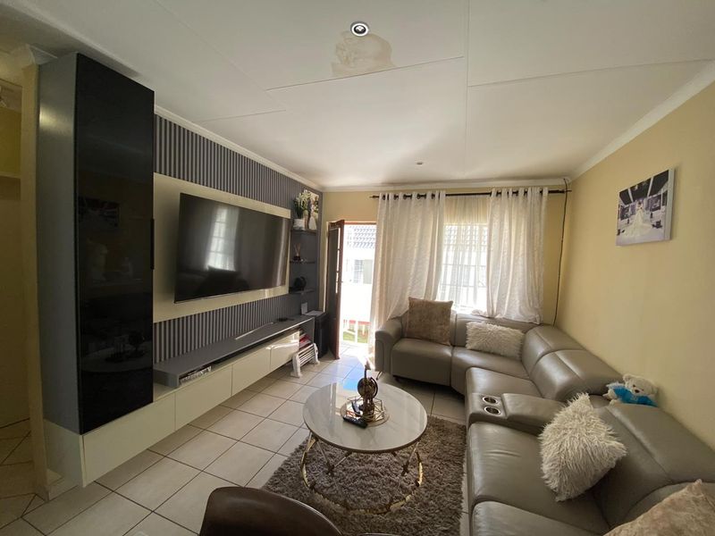 A living room featuring a built-in media unit, tiled flooring, and access to an outdoor area, showing a visible water stain on the ceiling.