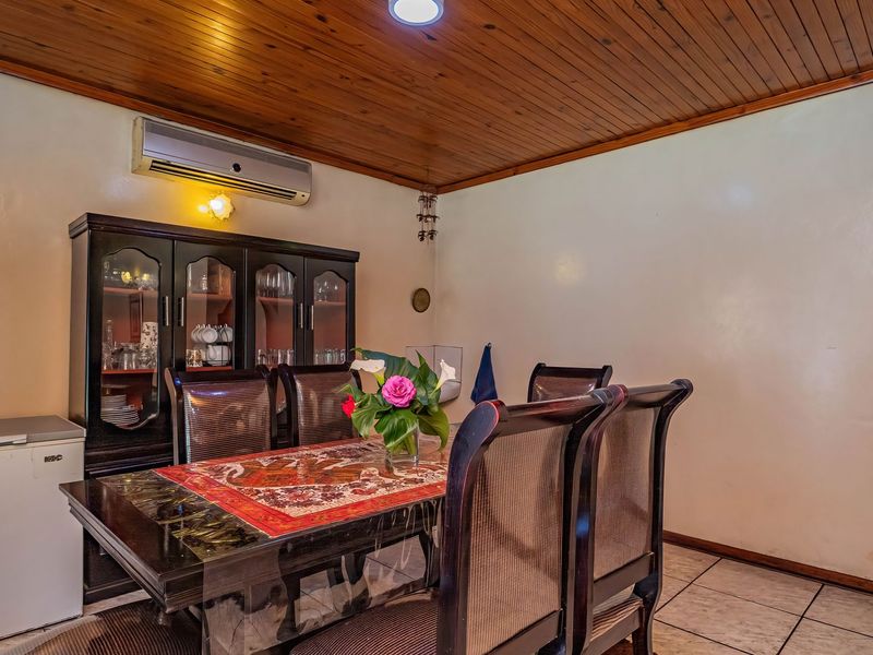 A dining room featuring a timber-paneled ceiling, tiled flooring, and a wall-mounted split-system air conditioner.