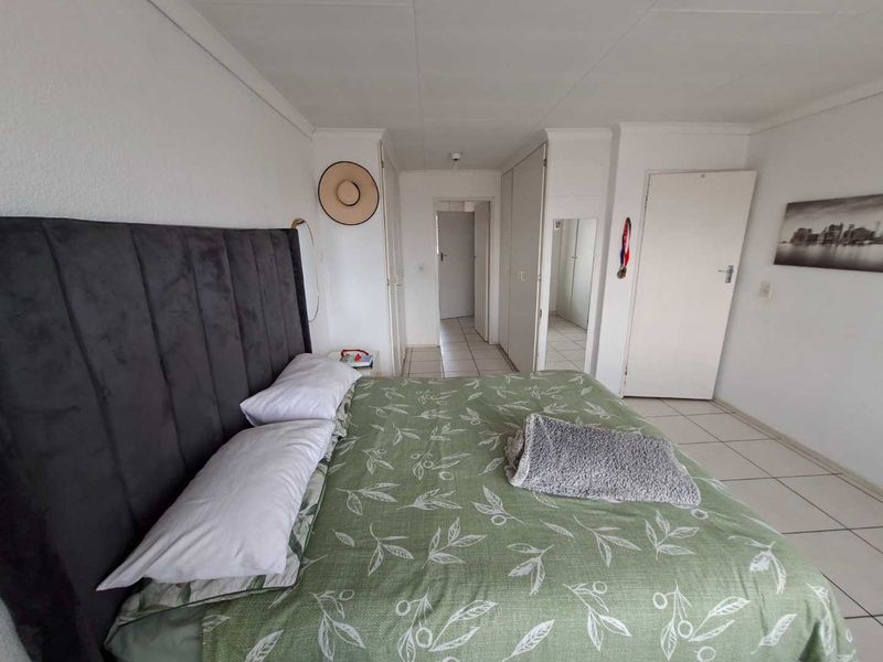 A functional bedroom featuring tiled flooring and built-in cupboards, providing practical storage space within the townhouse.