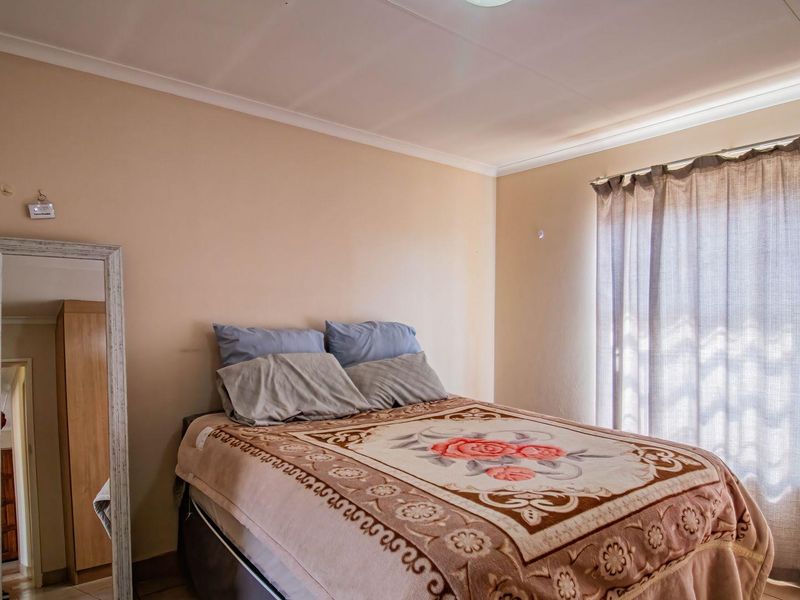 A standard bedroom featuring neutral wall finishes, cove cornicing, and a window fitted with a curtain rail.