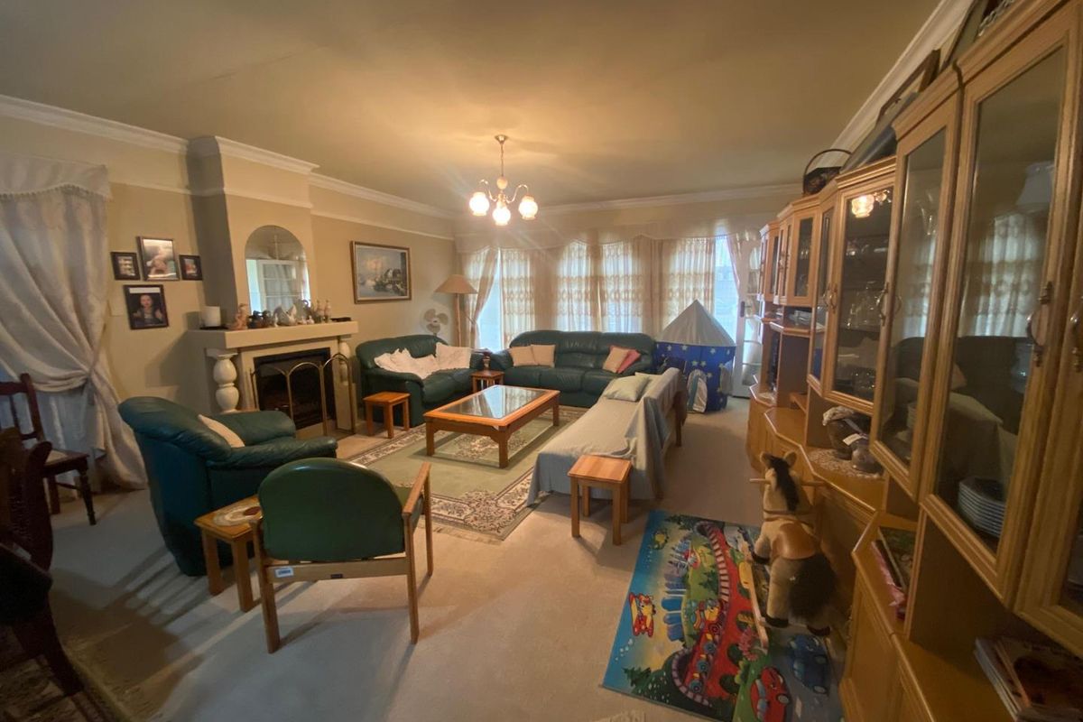A spacious living room featuring a traditional fireplace with a mantelpiece, crown molding, and large windows allowing for natural light.