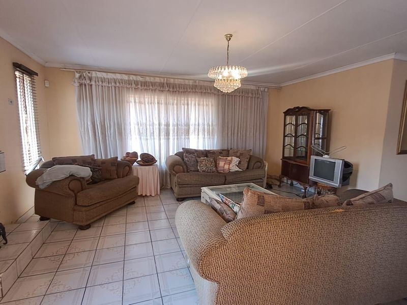 Spacious living room featuring tiled flooring, a built-in fireplace, and a classic ceiling light fixture, offering a comfortable and functional living space.