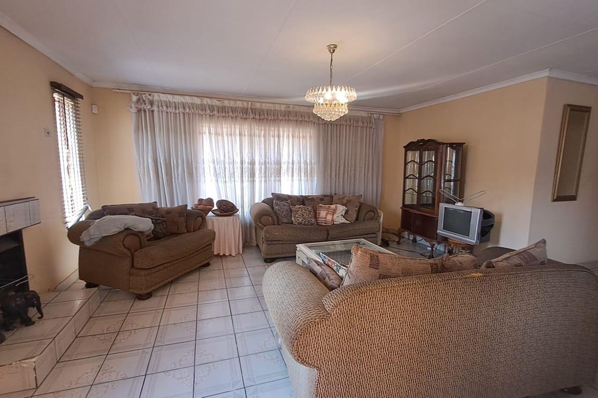 Spacious living room featuring tiled flooring, a built-in fireplace, and a classic ceiling light fixture, offering a comfortable and functional living space.