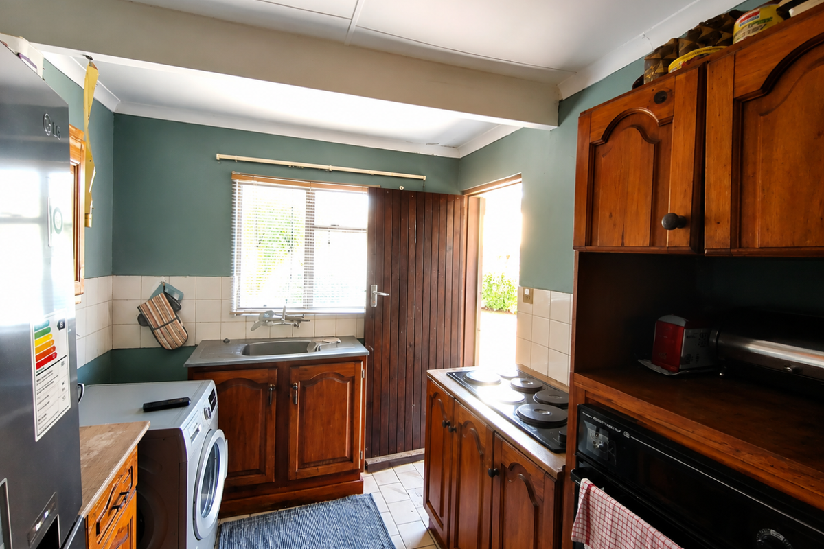 A functional kitchen featuring traditional wooden cabinetry, built-in oven and hob, tiled splashbacks, and direct access to the exterior.
