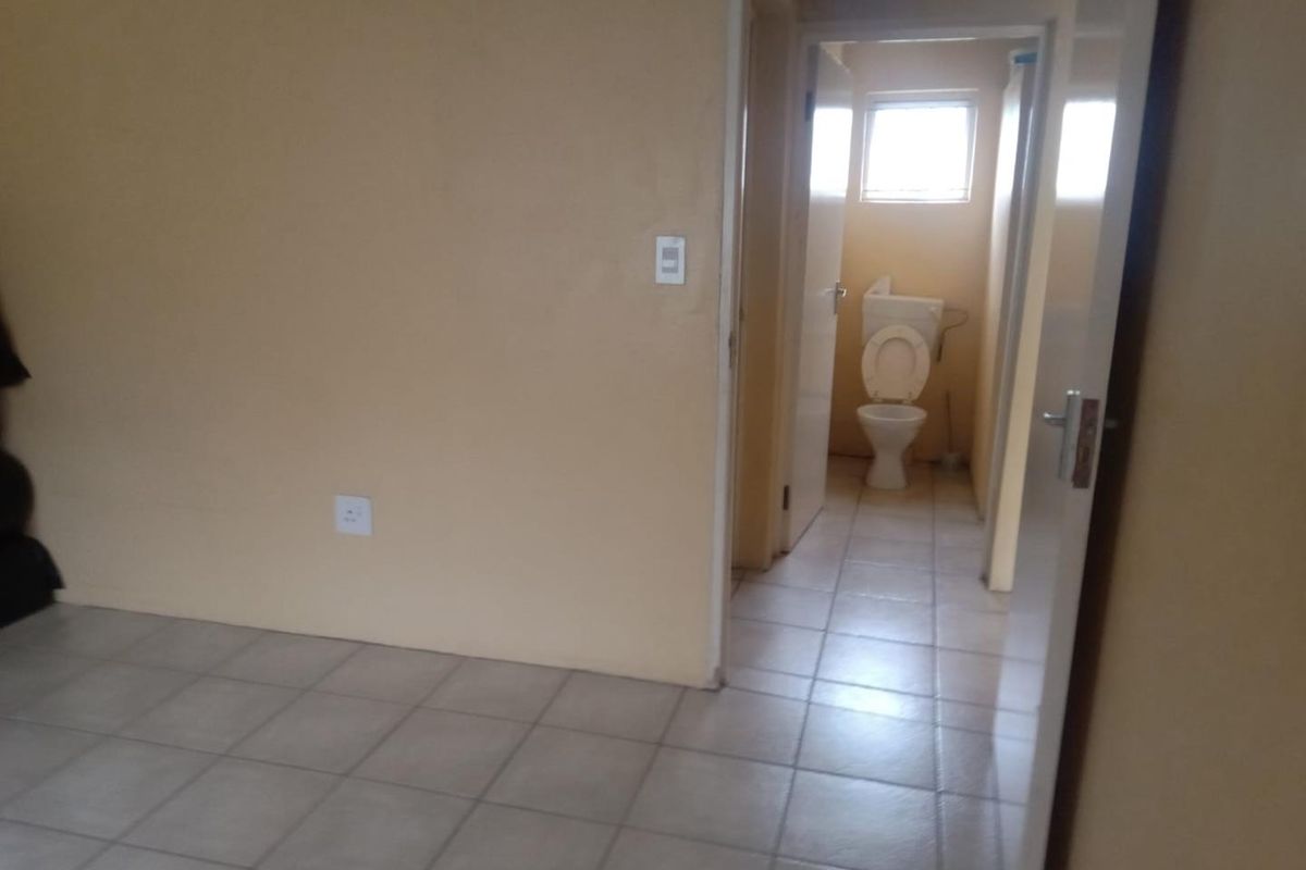 A view from a living area into a small bathroom featuring tiled flooring and basic sanitary ware.