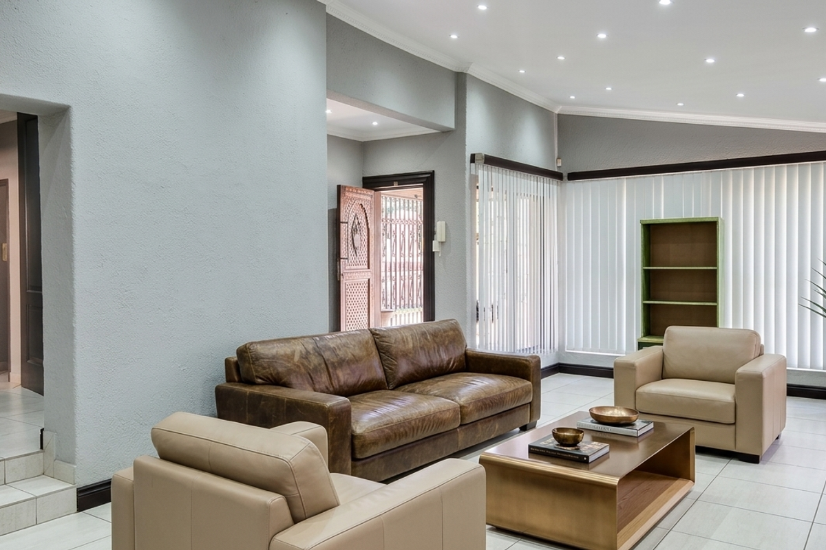 Spacious living room featuring neutral tiled flooring, recessed downlighting, and large windows with vertical blinds, creating a bright and inviting atmosphere.