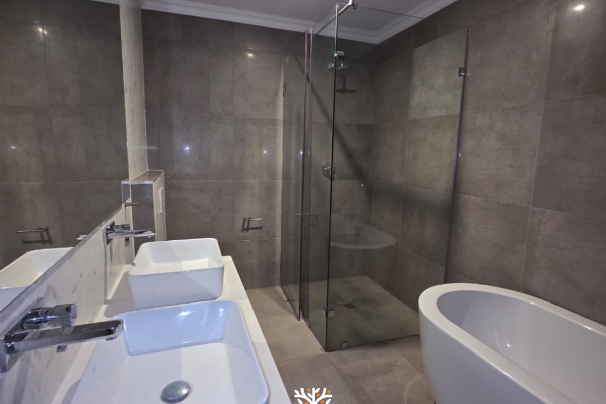 Modern bathroom featuring a double vanity with vessel sinks, a freestanding bathtub, and a frameless glass walk-in shower with large-format grey wall tiles.