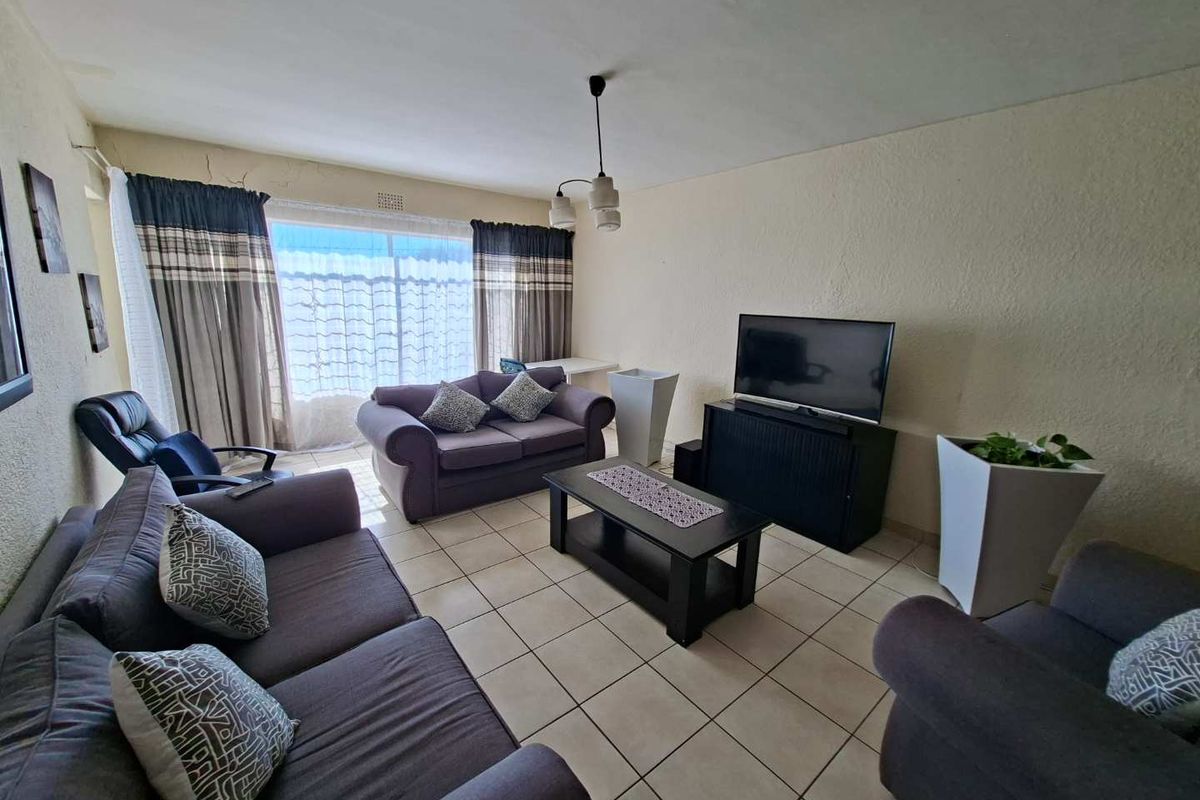 A living room featuring tiled flooring and a large sliding glass door providing natural light.