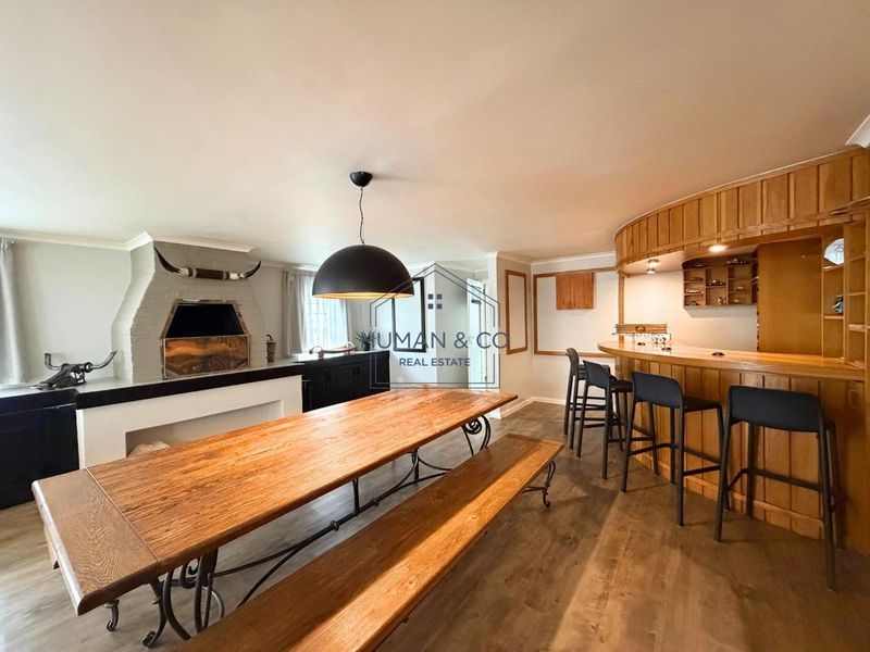 Spacious living area featuring a built-in wooden bar, indoor fireplace, and modern laminate flooring, ideal for entertaining.