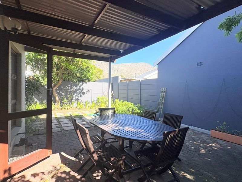 A covered outdoor patio area featuring paved flooring and a corrugated metal roof, providing a functional space for outdoor dining and relaxation.