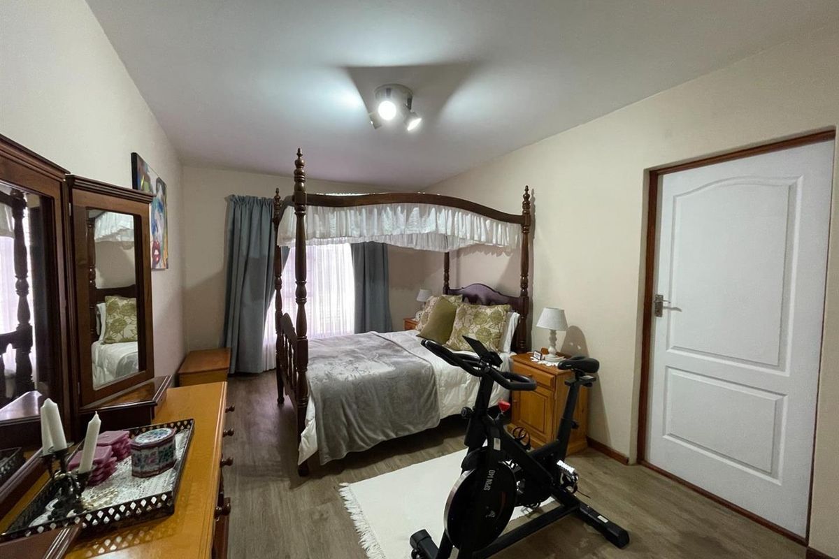 A bedroom featuring wood-look laminate flooring, a central ceiling light fixture, and a standard interior door.