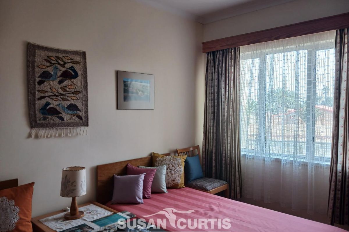 A bedroom featuring a timber curtain pelmet and aluminium window frame, offering natural light and a view of the surrounding area.