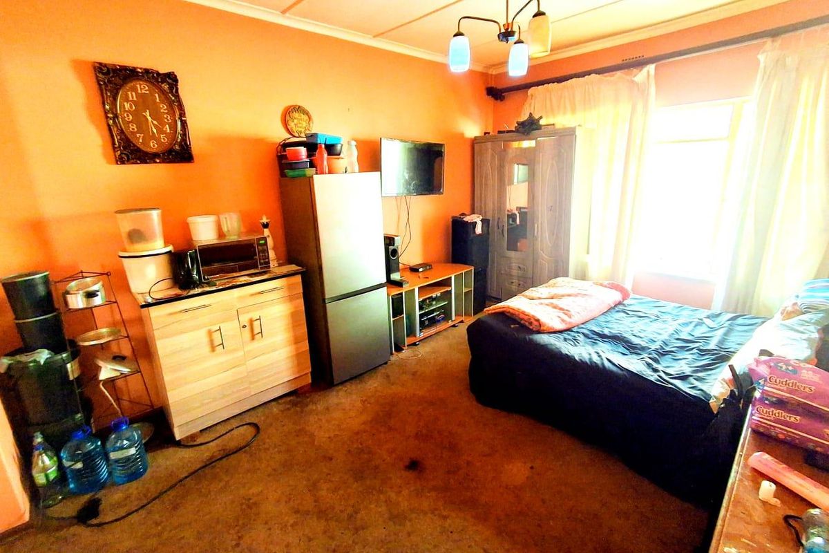 A bedroom featuring a built-in wardrobe, central light fixture, and large window, currently utilized as a multi-purpose living space.