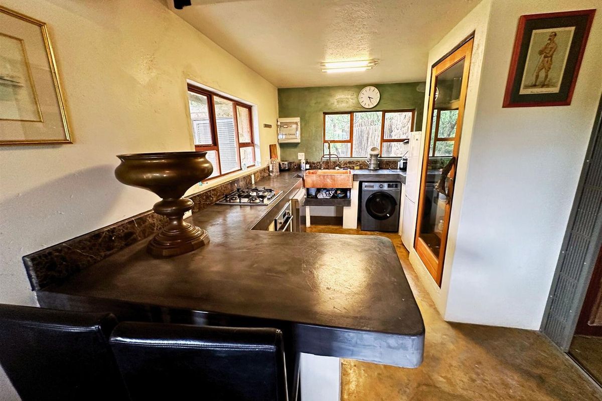 A functional kitchen featuring dark concrete countertops, a copper farmhouse sink, built-in gas hob, and integrated laundry appliance space.