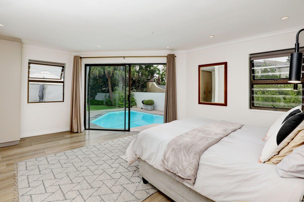 Spacious bedroom featuring wood-look flooring, recessed lighting, and sliding glass doors providing direct access to the private swimming pool area.