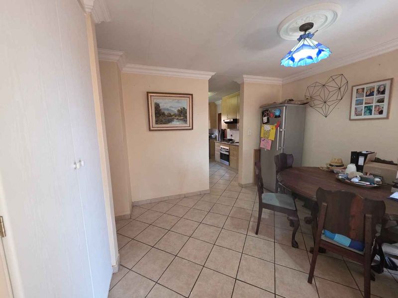 Open plan dining area with tiled flooring and cornicing, leading through to a functional kitchen space.