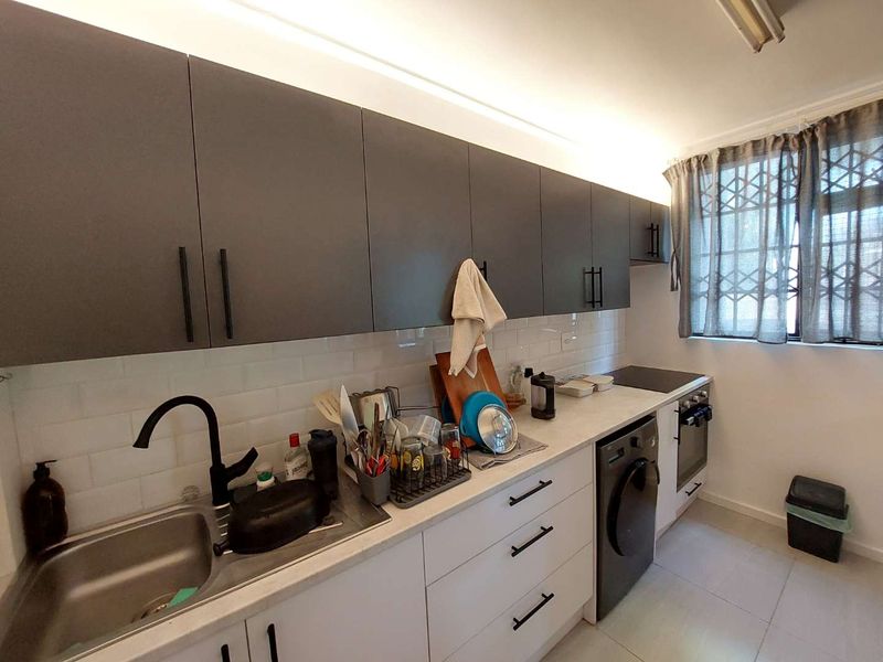 Modern kitchen featuring dark upper cabinetry, white lower cabinets, subway tile backsplash, and integrated appliances including an oven and hob.