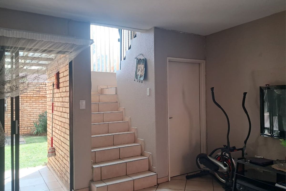 Interior view of a living area featuring tiled flooring, a staircase leading to the upper level, and sliding glass doors opening to the garden.