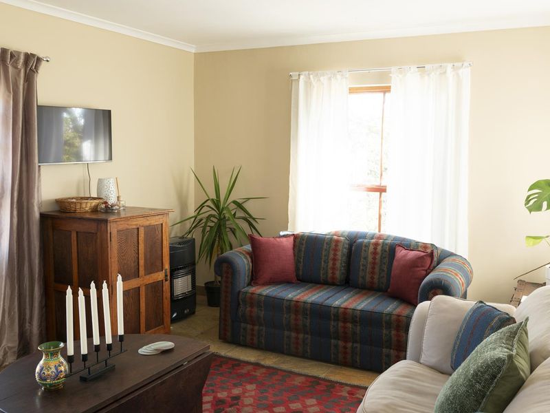 A comfortable living room featuring neutral wall tones, coving, and natural light from the window.
