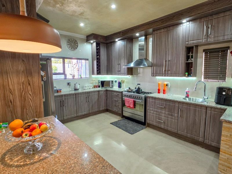 Modern kitchen featuring wood-grain cabinetry, granite countertops, stainless steel appliances, and integrated under-cabinet lighting for a functional and stylish workspace.