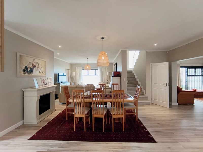 Spacious open-plan living and dining area featuring a fireplace, staircase, and modern laminate flooring with neutral wall tones.
