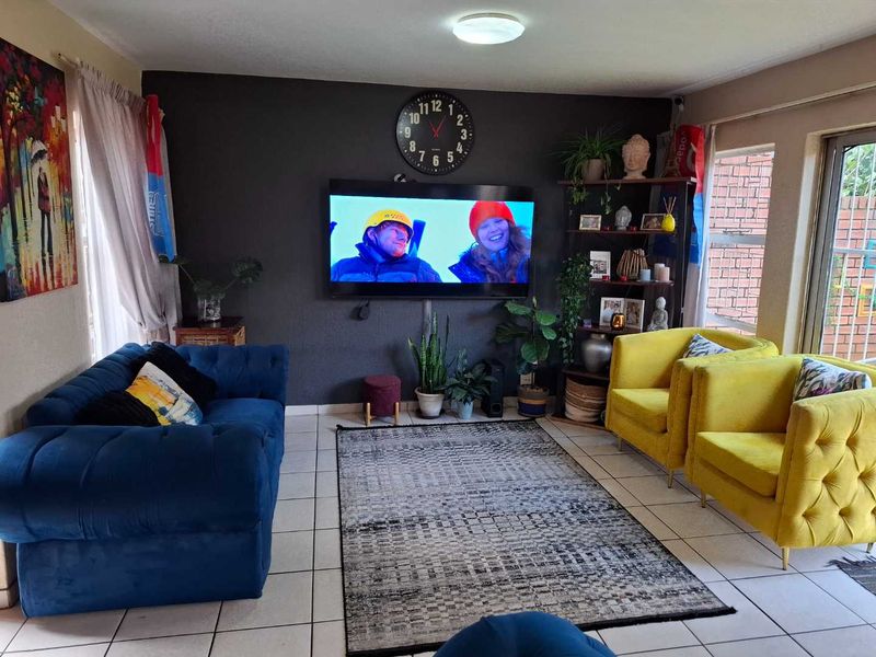 A living room featuring tiled flooring, a dark accent wall, and a sliding glass door providing access to the exterior.