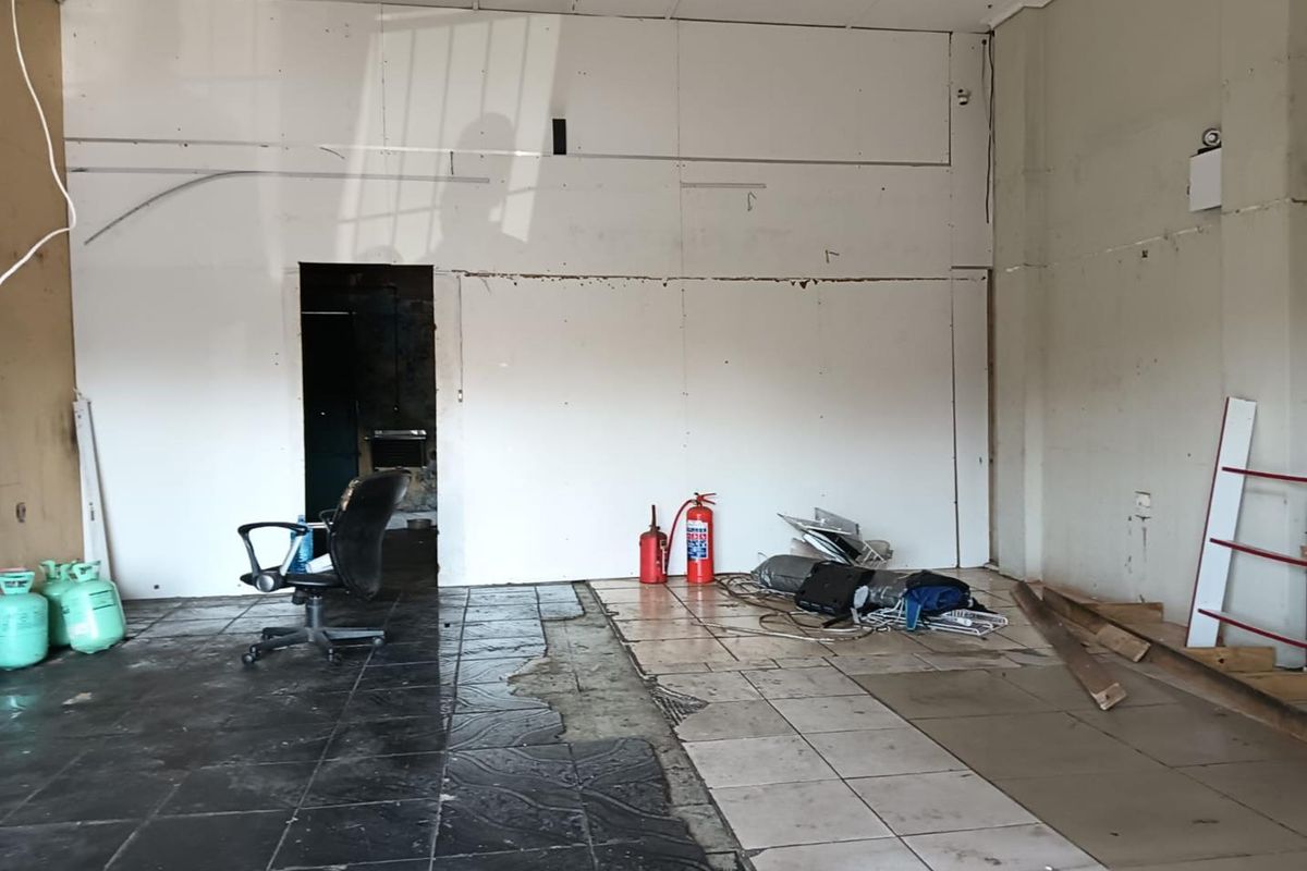 An empty commercial space featuring mixed tiled flooring and unfinished wall surfaces, requiring renovation and repair to restore functionality.