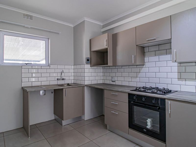 Modern kitchen featuring neutral cabinetry, subway tile backsplash, gas hob, built-in oven, and tiled flooring in a clean, well-maintained space.