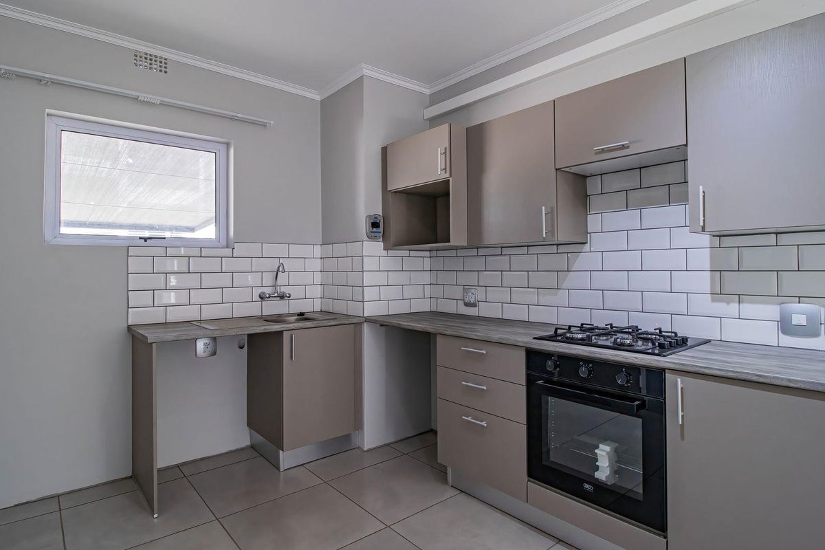 Modern kitchen featuring neutral cabinetry, subway tile backsplash, gas hob, built-in oven, and tiled flooring in a clean, well-maintained space.