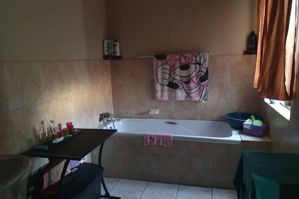 A functional bathroom featuring a built-in bathtub with tiled surround and wall tiling, providing a practical space for daily use.