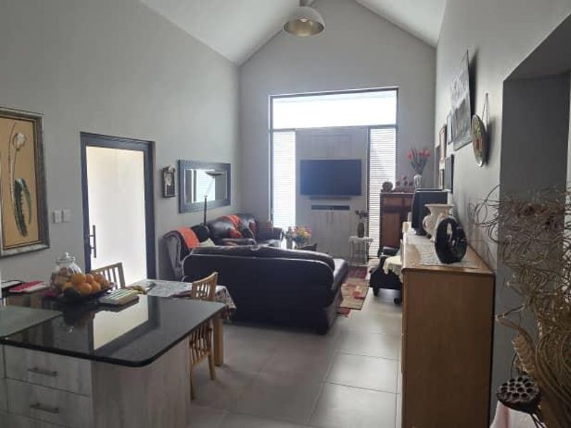 Spacious open-plan living area featuring a modern kitchen with granite countertops, vaulted ceilings, and large windows providing ample natural light.
