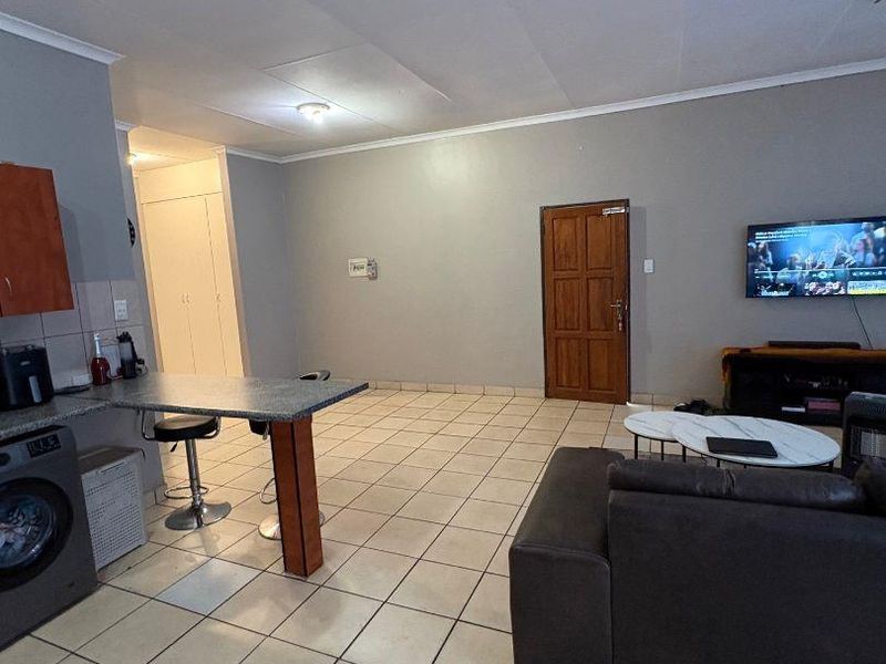 Open plan living area featuring tiled flooring, a breakfast counter with built-in cabinetry, and direct access to adjacent rooms.
