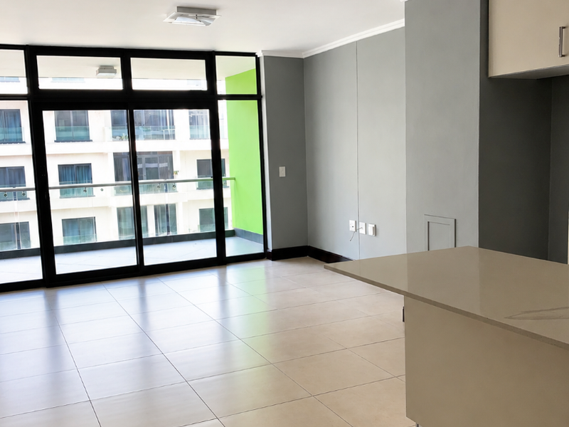 Spacious open-plan living area featuring large sliding glass doors leading to a balcony, tiled floors, and a modern kitchen island with built-in cabinetry.