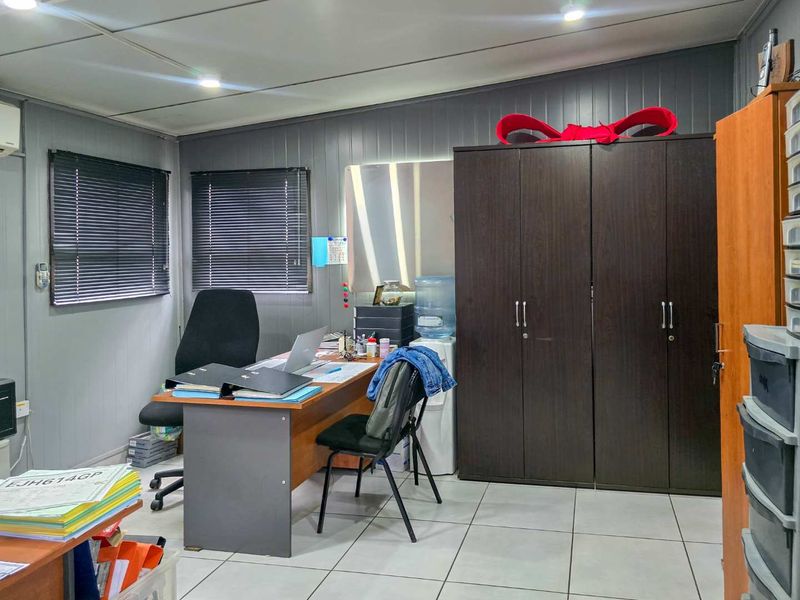 A functional office space featuring tiled flooring, recessed lighting, venetian blinds, and a built-in storage cupboard.