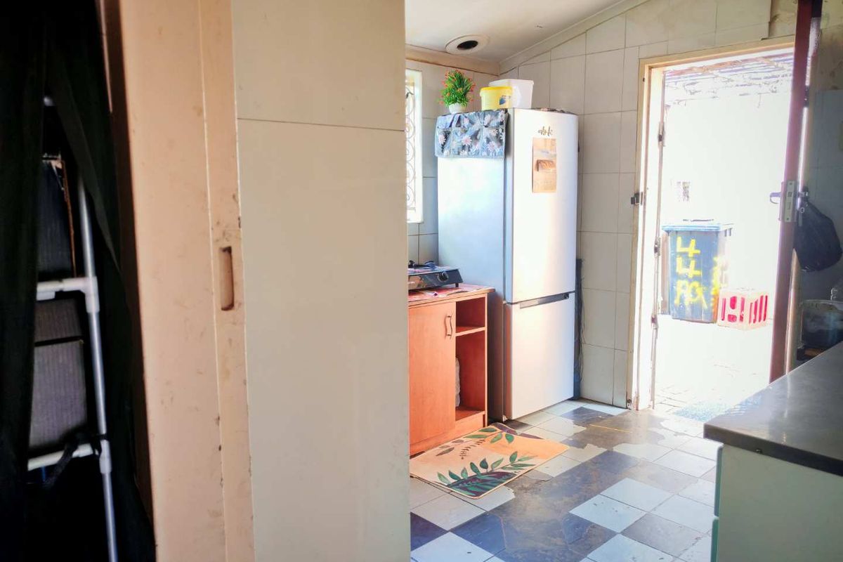 A functional kitchen area featuring tiled flooring, built-in cabinetry, and direct access to the exterior rear of the property.
