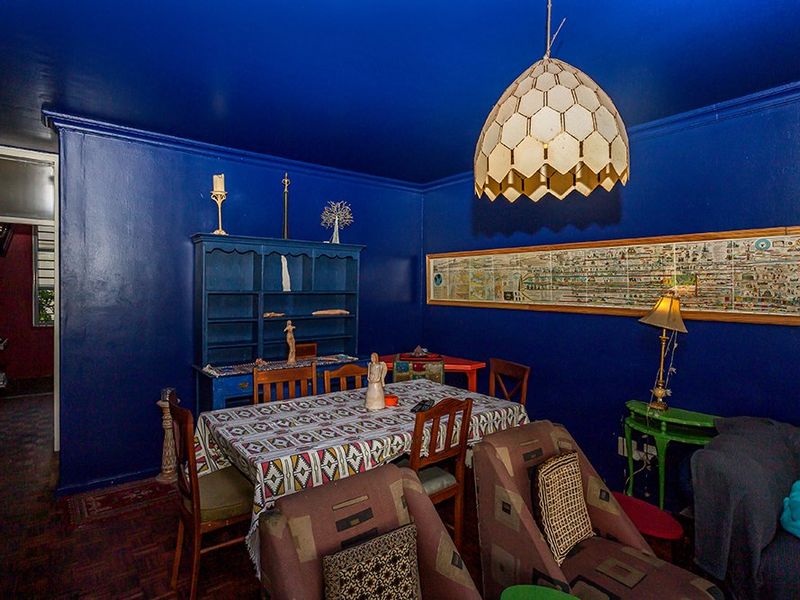A living room featuring dark blue walls, parquet flooring, and a built-in shelving unit, offering a distinct and bold interior aesthetic.