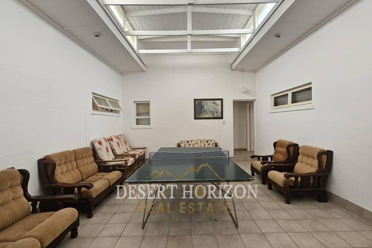 Spacious indoor entertainment area featuring a high vaulted ceiling with skylights, tiled flooring, and multiple windows providing natural light.