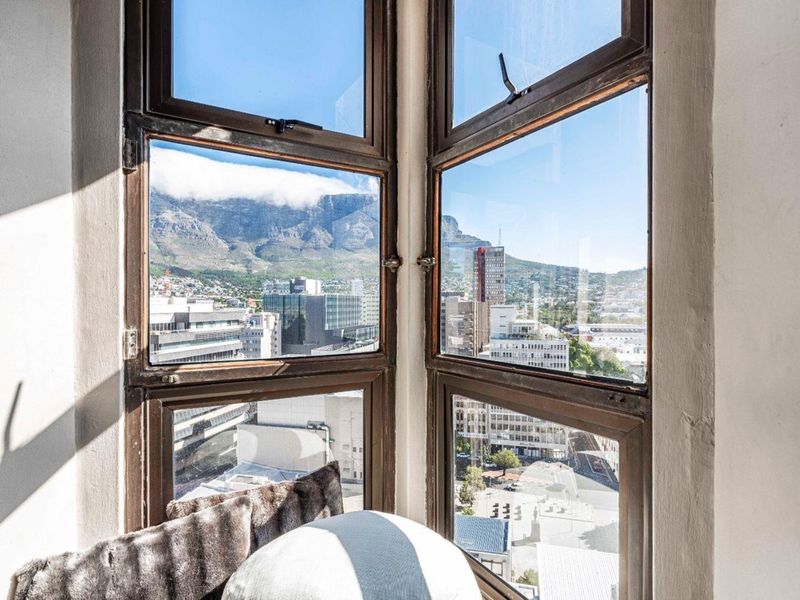 A view of the city and mountain framed by large casement windows in an apartment.