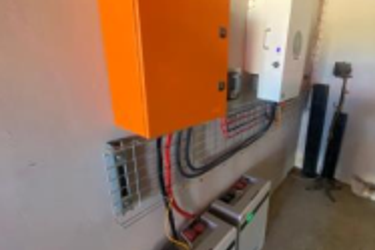 Utility area featuring a wall-mounted solar inverter and lithium battery storage system for off-grid power management.