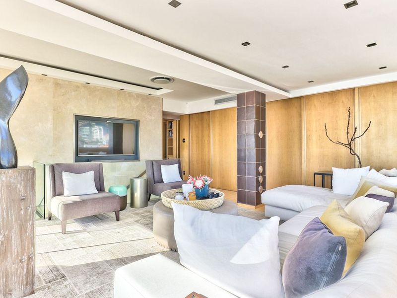 Spacious living room featuring stone wall cladding, integrated television niche, timber paneling, and recessed ceiling lighting with ducted air conditioning.